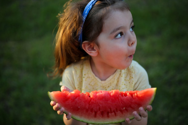 可爱的小女孩在吃新鲜的西瓜水果在花园库存照片图片下载