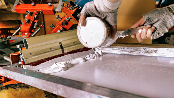 选择性聚焦照片的印刷筛选设备，可以白漆和一个工人的手。绢印生产。用丝印法在衣服上印刷图案图片下载