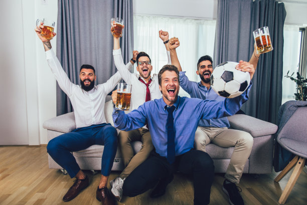 一群在电视上观看足球赛并庆祝进球的足球迷。图片下载