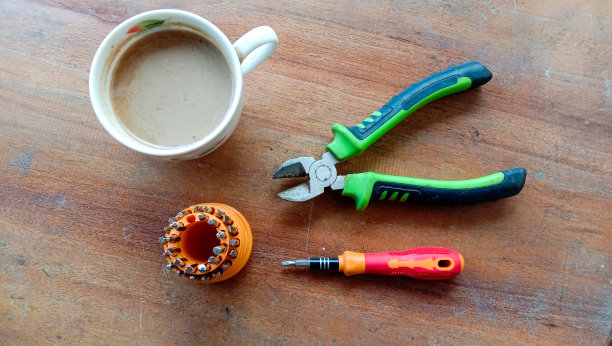 一张照片，一杯牛奶咖啡和一些工具，如螺丝刀，一个小树枝切割机在木桌子的背景图片下载