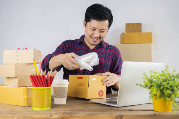 年轻快乐的企业主将防震材料和防震塑料包装成纸板箱图片下载