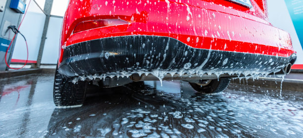 肥皂和水从一辆洗过的红色汽车的挡泥板上流下来。图片下载