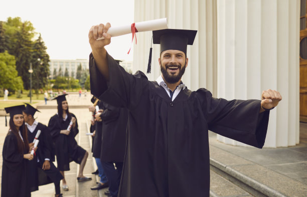 高兴的毕业生与文凭卷轴图片下载