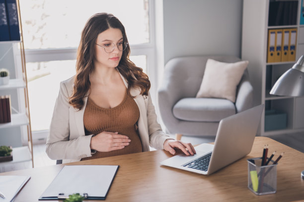 照片肖像孕妇工作在笔记本电脑打字浏览在现代办公室图片下载