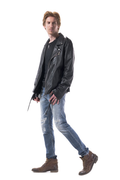 侧面的英俊的骑自行车的人或摇滚歌手走着，自信地看着后面。图片下载