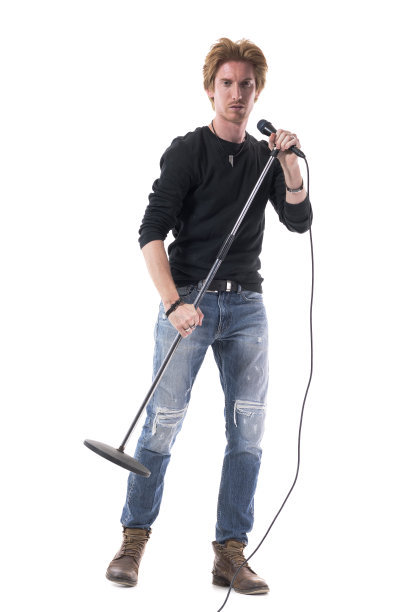 金发摇滚歌手拿着麦克风站着看着镜头。图片下载