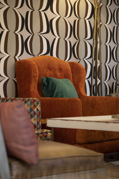 色彩缤纷的客厅装饰有一个橙色的沙发旁边的靠垫和一张木桌，家具在家庭内部，背景与纹理墙纸，工作室图片下载