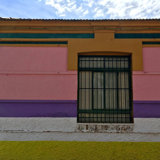 黄色、白色、紫色、粉色、绿色的房屋立面特写，配以大窗户、蓝天和白云，带有复制空间图片下载