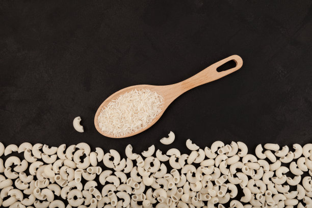 木勺白米和由米粉制成的健康无麸质面食产品。深色纹理背景，复制空间图片下载