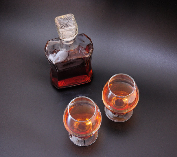 两个玻璃杯和一个玻璃瓶，白兰地在黑色背景上。图片下载