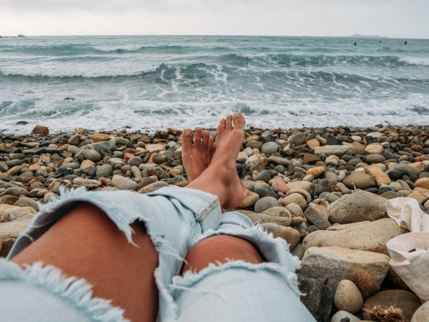 在撒丁岛的卵石海滩上放松的女人，日落图片下载
