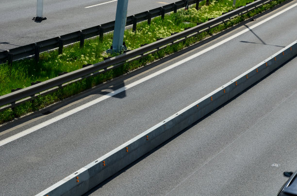 水平道路标志车道。公路上有混凝土护栏。车辆碰撞车道分隔符。黄色带黑色条纹。指示橙色闪光方向的光锥图片下载