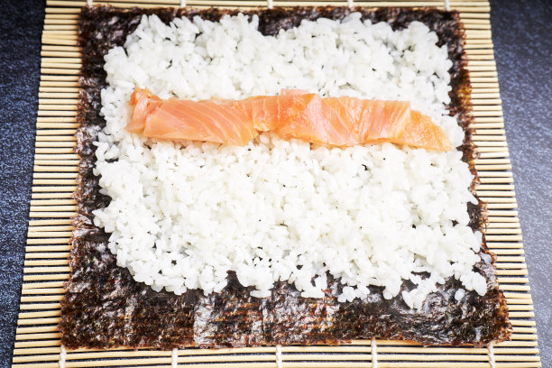 女厨师正在为美味的寿司准备海苔米饭。亚洲食品的概念。健康食品。暗的背景图片下载
