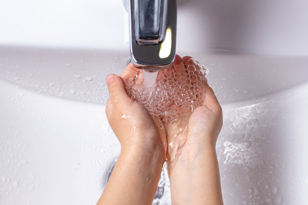 一个孩子在浴室的水龙头上洗手的俯视图。图片下载