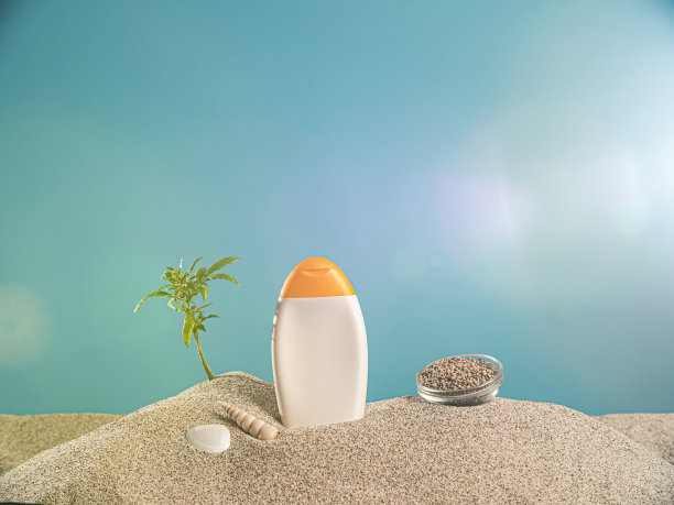 来自CBD产品和沙子中的大麻植物枝条的防晒霜图片下载