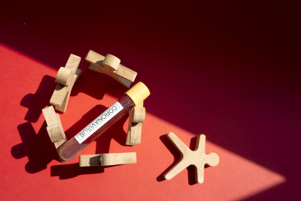 带着试管的木头人。阳光直射下的阴影在红纸背景上。图片下载