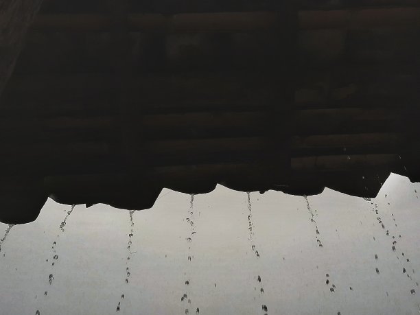 雨点从屋顶在阴天与外面的天空背景。多云的背景。图片下载