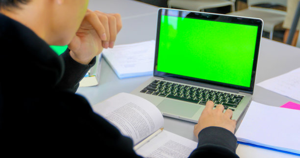亚洲学生使用绿色屏幕的笔记本电脑和平板电脑工作图片下载