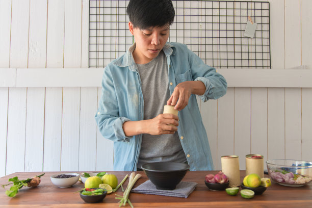 亚洲人在餐桌上用蔬菜、韭菜、柠檬草、青柠叶打开鱼罐头，制作出一份鱼罐头沙拉菜单。泰国菜。在家里厨房做饭准备工作图片下载