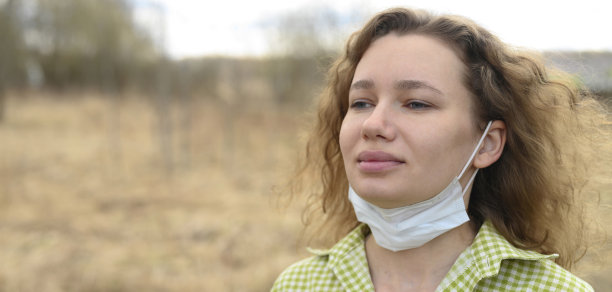 结束隔离和隔离COVID-19冠状病毒概念。一名30岁的年轻欧洲妇女摘下医用口罩，到户外大自然中呼吸新鲜空气图片下载