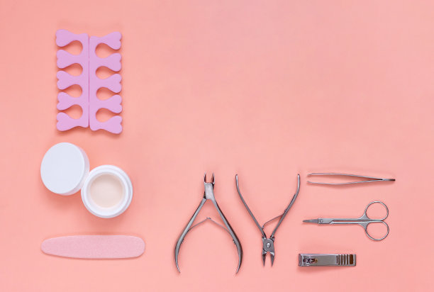 一套美甲和足疗工具与文本的复制空间。粉色背景的美容设备。美甲沙龙仪器，俯视图。图片下载