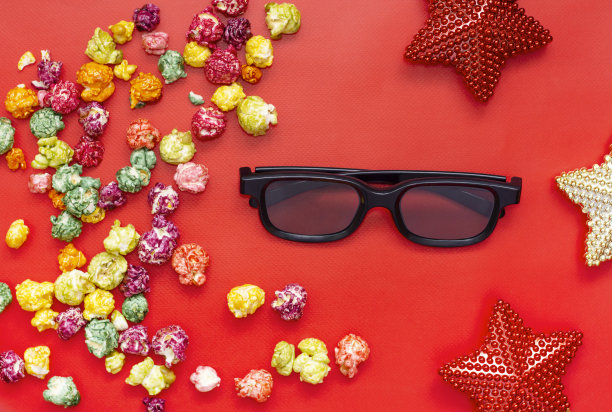 假日电影。电影院，电影时代概念。爆米花，3d眼镜，红色背景上的圣诞明星。图片下载