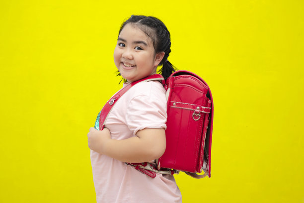 可爱的女学生背着书包，冰淇淋孤立在黄色的背景上图片下载