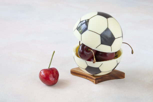 欧洲足球的巧克力球，里面有樱桃浆果。现代甜点概念，为健康观看足球比赛与美味的小吃图片下载