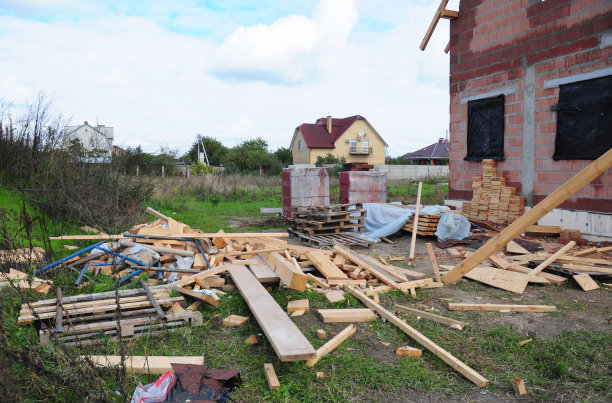 建筑工地一片混乱。在未完工的在建房屋附近，散落着木板、椽、砖等建筑材料。图片下载