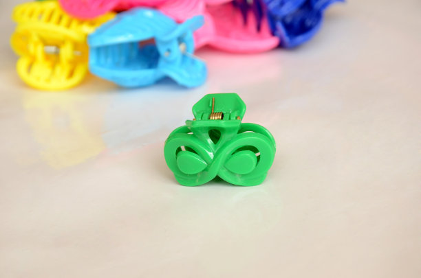 小绿色塑料发夹与彩色cloture隔离在白色背景。图片下载