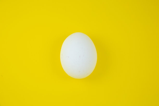 黄色背景上的白色鸡蛋。副本的空间。极简主义，原创和创意的照片。漂亮的壁纸。复活节假期。图片下载
