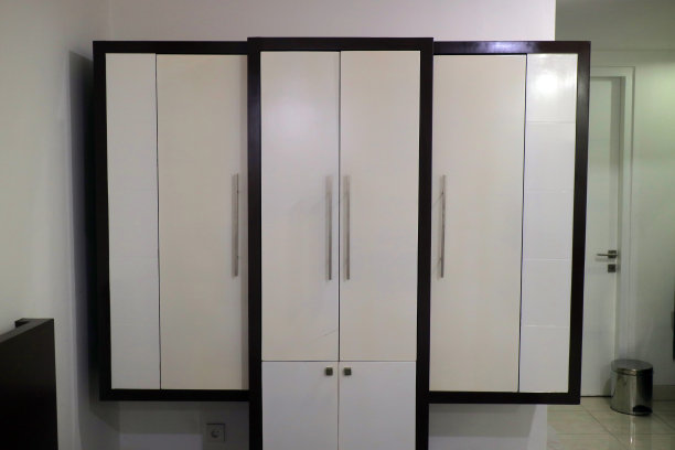 有三扇门的白色衣柜靠在墙上的照片图片下载
