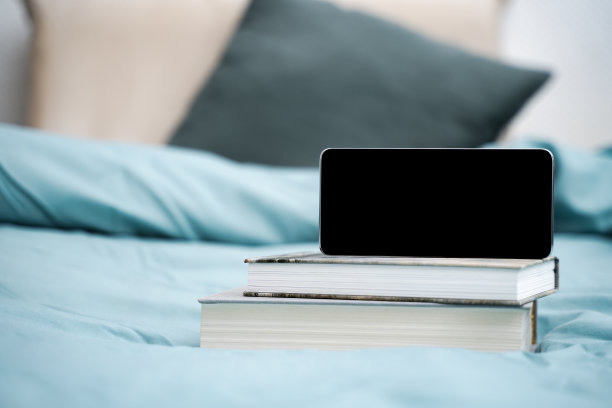 空白手机在一堆书和床的背景和枕头图片下载