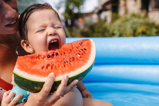 蹒跚学步的孩子在充气泳池里吃西瓜图片下载