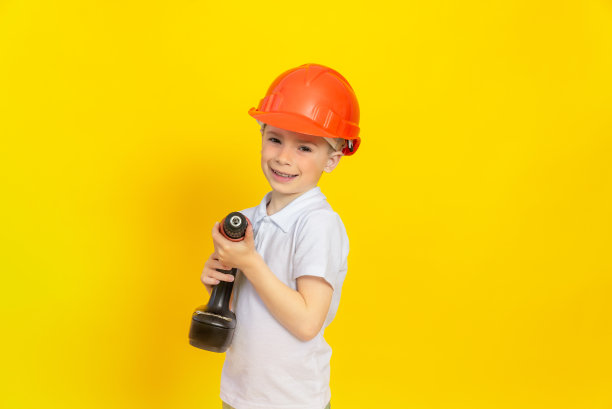 一个快乐的男孩手里拿着一个用于建筑的电动工具。在家庭装修过程中帮助孩子父母的理念。图片下载