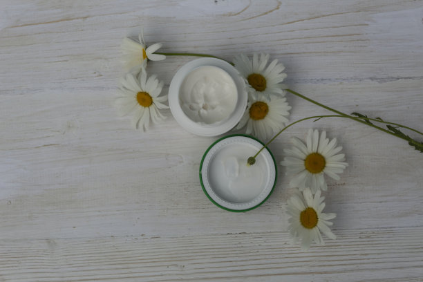 有洋甘菊和一瓶开着的面霜图片下载