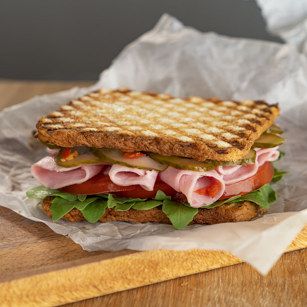 美味的三明治，有芝麻菜，西红柿和黄瓜。新鲜的火腿薄片。一份快餐。有选择性的重点。图片下载