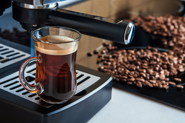 透明杯咖啡近景正面。家庭咖啡机和咖啡饮料的制作过程。从咖啡豆和复制空间散焦。图片下载