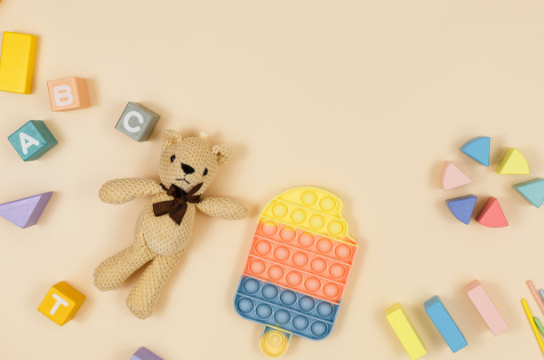 流行的硅酮软粉抗应力弹它的玩具，木制立方体，泰迪熊的米色背景。时髦的感官坐立不安玩具。幼儿园或学龄前的游戏。图片下载