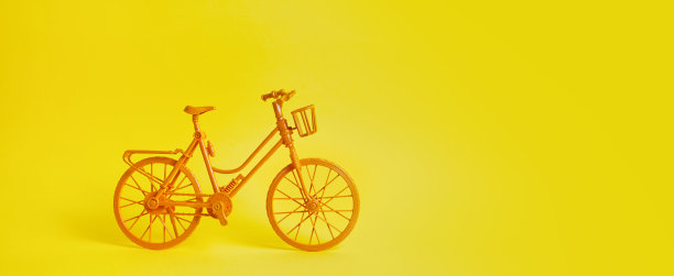 那辆老式的黄色自行车停在黄色的墙边。图片下载