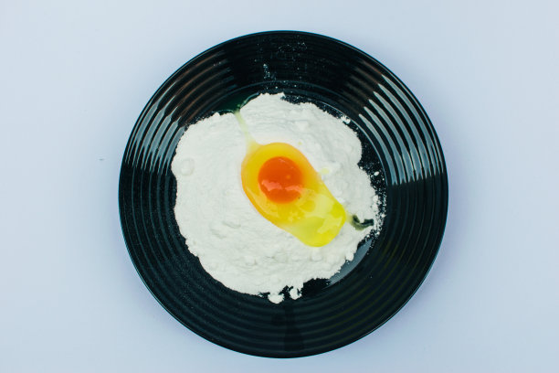 黑色盘子与鸡蛋和面粉存货照片图片下载