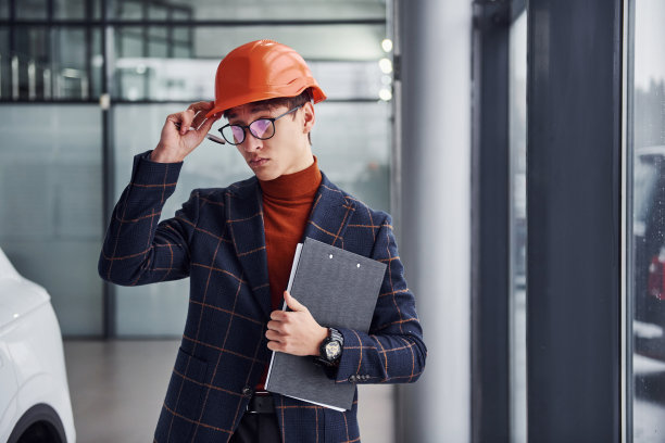 年轻男子的肖像，在保护头盔和正式的衣服，站在室内图片下载