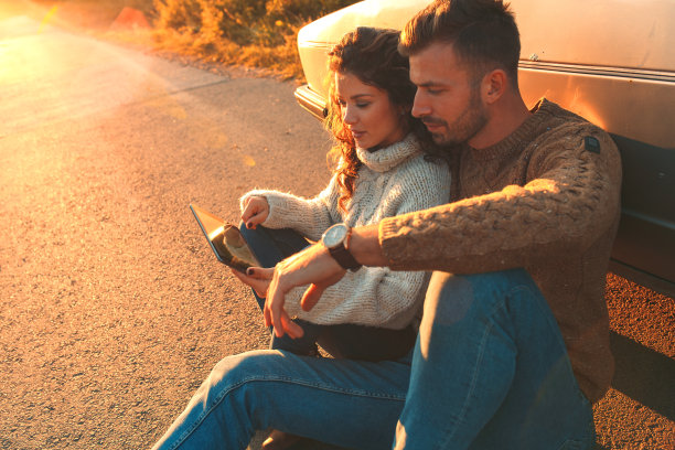 这对漂亮的情侣在公路旅行中，他们正在从开车中休息，在平板电脑上寻找方向。图片下载