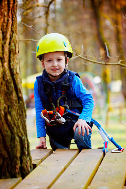 快乐的小男孩的肖像在冒险公园的乐趣，微笑着戴着头盔和安全设备的相机。图片下载