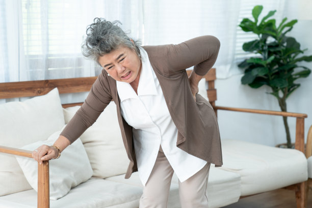 年长的亚洲妇女在家里遭受背痛。图片下载