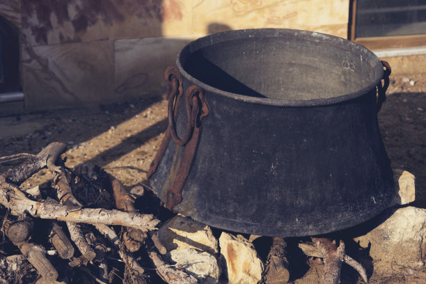 在阳光明媚的日子里，用满是煤烟的旧坩埚在篝火上做饭。特写镜头。复古的形象。图片下载
