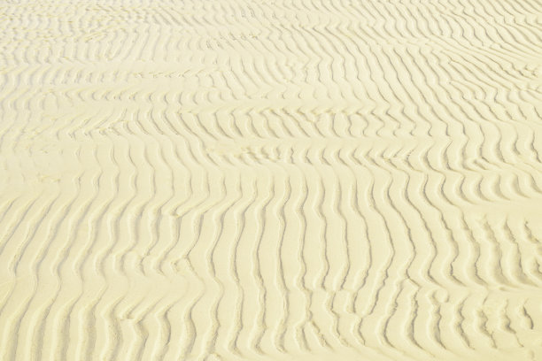 海岸上的沙子纹理。波浪沙背景特写。图片下载
