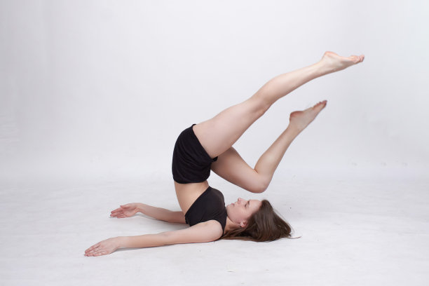 年轻苗条的运动女孩，长发，黑色上衣和短裤，在工作室的白色背景图片下载