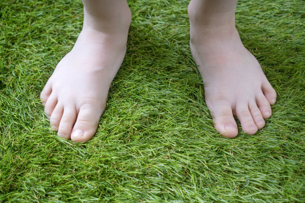 细嫩的孩子的腿近距离在柔软的人造草图片下载