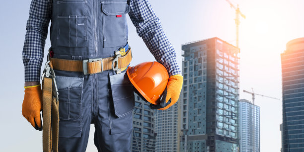 建筑工人穿著制服在工地使用安全带及安全帽。图片下载